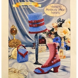 May include: A vintage-style image featuring miniature crochet items. A blue and red riding boot, a matching purse, and a hat are displayed. The text "Stepping Through Time Riding Boot" and "Annie's Miniature Shoe Society" are visible.
