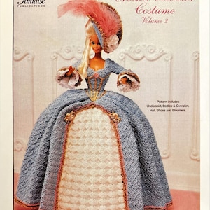 May include: A Barbie doll wearing a blue and white crochet 1775 French Court Dress costume. The doll has blonde hair and is wearing a hat with a pink feather. The image is from a "Crochet Collector Costume" pattern book.