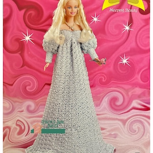 Può includere: Una bambola all'uncinetto vestita con un abito bianco con un rosa in mano. La bambola fa parte della "The Fairy Tale Collection" ed è intitolata "Sleeping Beauty".