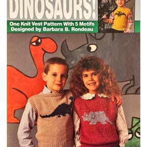 Könnte beinhalten: Bild eines Vintage-Strickmusterbuchs mit dem Titel "DINOSAURS!" mit einer beigefarbenen und roten Strickweste mit Dinosaurier-Motiven. Das Cover zeigt zwei Kinder, die die Westen tragen. Das Muster wurde von Barbara B. Rondeau entworfen.