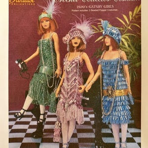 May include: A magazine cover showing three dolls in 1920s flapper costumes. The dolls are in beaded dresses of green, pink, and blue, with matching hats and feather details. The magazine is titled "Crochet Collector Costume."