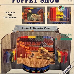 May include: A colourful plastic canvas pattern for a puppet show featuring a lion and mouse. The pattern is titled "Rainbow Theatre Puppet Show" and includes the text "Back Street Designs".