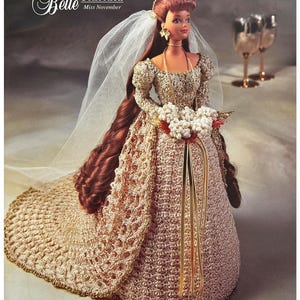 May include: A crocheted doll wearing a white veil and a gold dress with a white flower bouquet. The doll is part of the "The Bridal Belle Collection" and is labeled "Miss November".