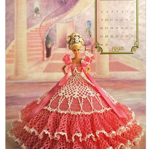 Puede incluir: Un patrón de vestido de crochet para una muñeca Barbie. El vestido es rosa y blanco con un diseño de encaje. La muñeca lleva una cinta rosa y una máscara. El patrón es de agosto de 1992.