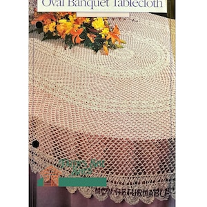 May include: A crocheted oval banquet tablecloth in a cream color with a delicate lace pattern. The tablecloth is shown on a table with a bouquet of orange and yellow flowers.