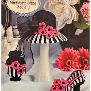 May include: A black and white striped crochet hat with pink flower accents, a matching purse, and a high-heeled shoe. The image also includes the text "Annie's Miniature Shoe Society" and "Stepping Out".
