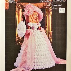 May include: A doll dressed in a pink and white crocheted gown, hat, and shawl, holding a parasol. The image is from a "Crochet Collector Costume" pattern book, volume 25, with the title "1850 Old South Gown."