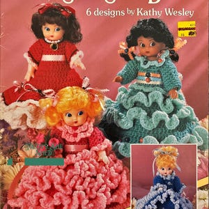 May include: A crochet pattern booklet for making six different Sweet Scents Dolls. The cover features four dolls in various crochet outfits, including a red dress, a teal dress, a pink dress, and a blue dress. The dolls are all 5 3/4 inches tall and fit air fresheners.
