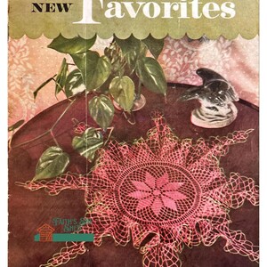 May include: A vintage crochet pattern book cover featuring a pink crochet doily on a dark brown table. The cover text reads "Old and New Favorites" and "Book No. 269".