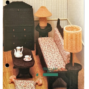 May include: A plastic canvas pattern for a dollhouse living room set. The set includes a sofa, two end tables, a lamp, a coffee table, a dresser, and a pillow. The pattern is titled "Fashion Doll Home Furnishings II".