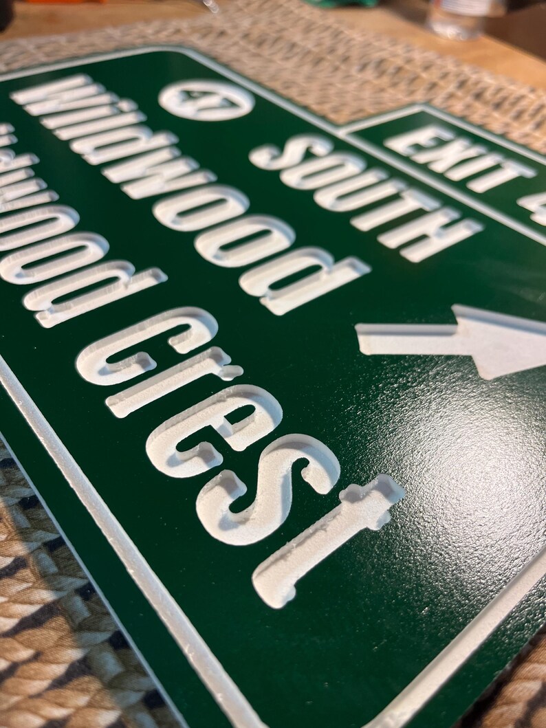 Puede incluir: Se&ntilde;al de direcci&oacute;n verde y blanca con las palabras "Wildwood Crest" y "South" visibles. La se&ntilde;al tambi&eacute;n indica "Salida 4" con una flecha. La se&ntilde;al tiene un acabado brillante.