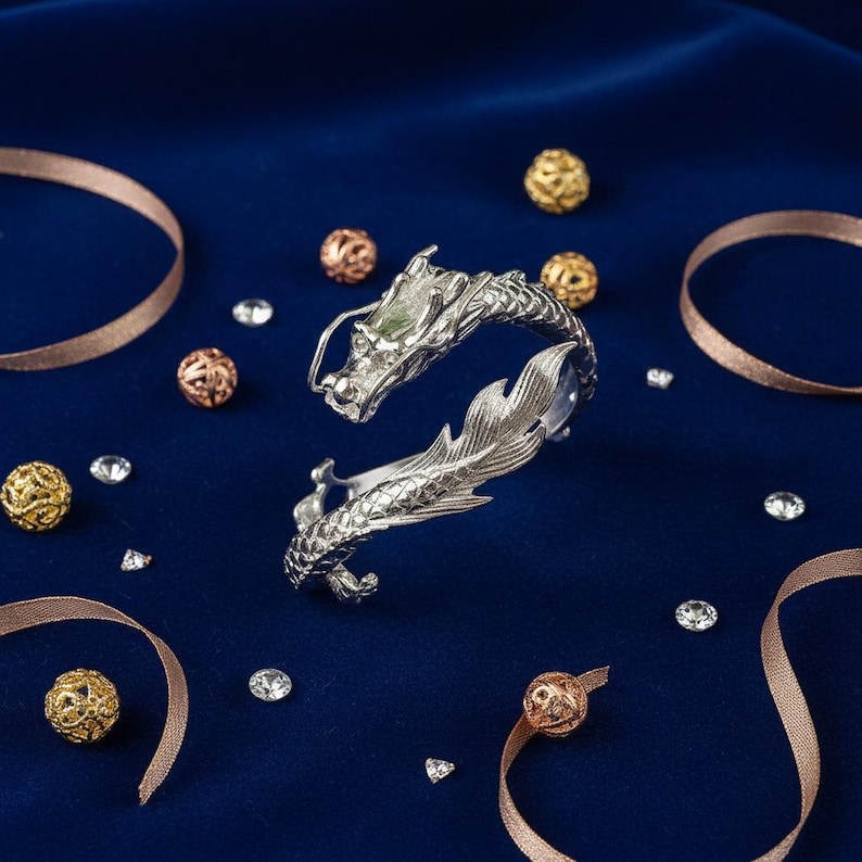 Close-up of a 925 sterling silver open cuff bracelet with two intricately detailed white dragon heads and a lustrous finish. The adjustable bangle flexes for a secure fit, blending mythical elegance with bridal-ready style.
