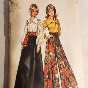 May include: A Simplicity 5235 sewing pattern envelope featuring illustrations of two outfits. One shows a white long-sleeved blouse with a black maxi skirt and red sash. The other shows a yellow long-sleeved blouse with floral print wide-leg pants.