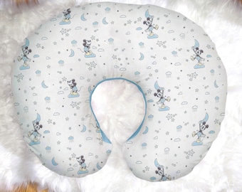 Op de afbeelding: Een blauw en wit voedingskussen met een Mickey Mouse print. Het kussen heeft een herhalend patroon van Mickey Mouse die een ster, een halve maan en kleine sterren vasthoudt.