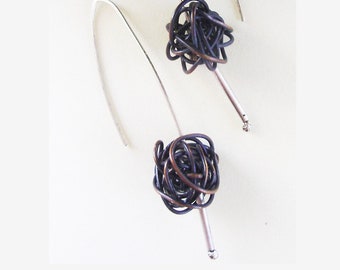 May include: A pair of silver earrings with a dark brown wire wrapped ball at the end of each earring.