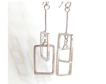 May include: A pair of silver dangle earrings with two square shapes, one inside the other.