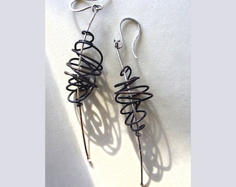 May include: A pair of silver and brown wire earrings with a spiral design. The earrings are long and dangle.