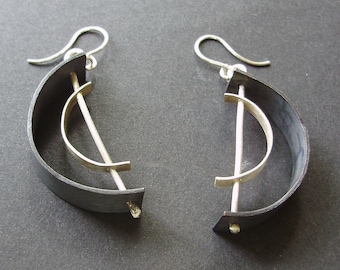 May include: A pair of silver earrings with black curved metal accents. The earrings feature a silver bar with a curved silver piece attached to it.