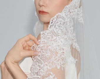May include: A white bridal veil with a delicate lace trim. The veil is made of soft tulle and features a floral pattern.