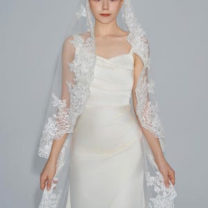 May include: A white bridal veil with delicate lace trim. The veil is made of soft tulle and features a scalloped edge.