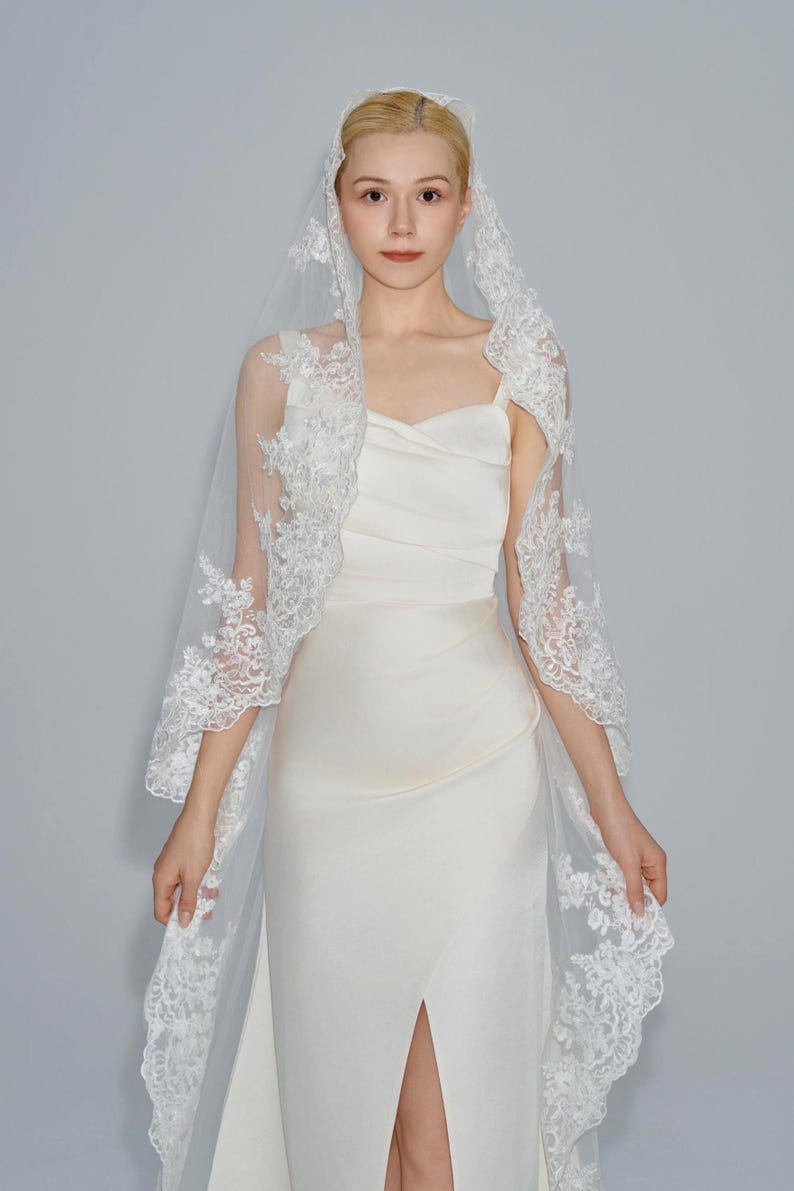 May include: A white bridal veil with delicate lace trim. The veil is made of soft tulle and features a scalloped edge.