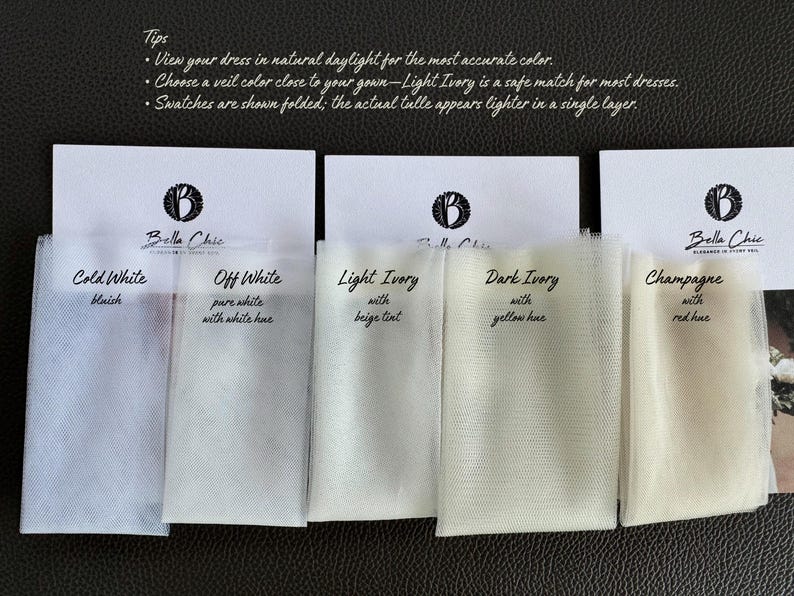 Op de afbeelding: Een selectie van tule stofstalen in verschillende tinten wit en ivoor, waaronder Cold White, Off White, Light Ivory, Dark Ivory en Champagne. Elk staal is voorzien van een kleurbeschrijving. Het Bella Chic logo is zichtbaar.