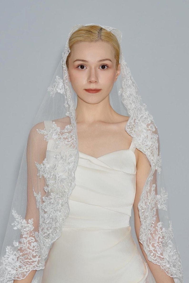 May include: A white bridal veil with delicate lace trim. The veil is made of soft tulle and features a scalloped edge.