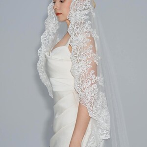 May include: A white bridal veil with a delicate lace trim. The veil is made of soft tulle and features a floral pattern.