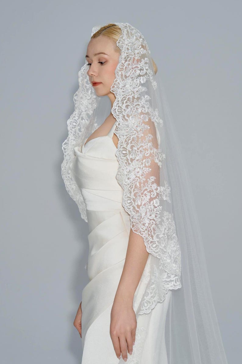 May include: A white bridal veil with a delicate lace trim. The veil is made of soft tulle and features a floral pattern.
