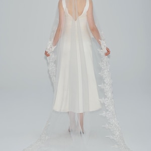 May include: A white bridal veil with a delicate lace trim. The veil is long and flowing, with a scalloped edge.