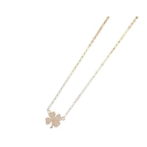 May include: A gold chain necklace with a small, four-leaf clover pendant encrusted with clear cubic zirconia stones.