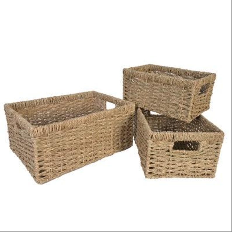 Peut inclure: Trois paniers de rangement rectangulaires tress&eacute;s de diff&eacute;rentes tailles. Les paniers sont faits d'un mat&eacute;riau brun clair et ont des poign&eacute;es int&eacute;gr&eacute;es. Les paniers sont empil&eacute;s ensemble.