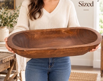 May include: A large, oval-shaped wooden dough bowl with a smooth, dark brown finish and visible wood grain. The text "Generously Sized" is printed in dark brown lettering above the bowl, which is held horizontally.