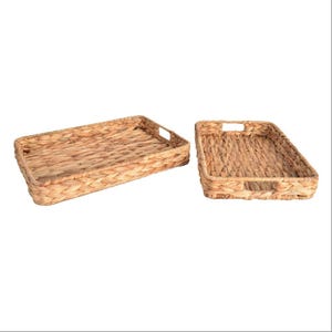May include: Two rectangular woven trays made of natural-colored material. Each tray has a handle cut out on either side. The trays are empty and sit on a white background. The trays are likely used for serving or decorative purposes.
