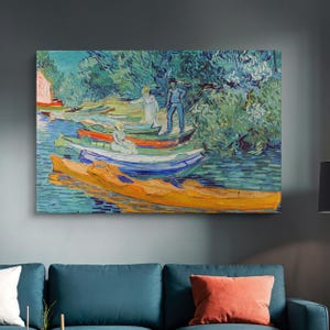 Pode incluir: Uma pintura que retrata uma cena de rio com vários barcos atracados na margem. Os barcos são pintados em vários tons de azul, verde e amarelo. Duas figuras estão na margem, uma com uma camisa azul e a outra com um vestido branco. O fundo é uma floresta verdejante.