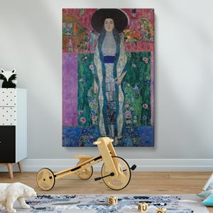 May include: A painting of a woman in a white dress and a blue sash, standing in front of a green and pink background with flowers. The woman is wearing a black hat and has long dark hair.