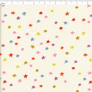 May include: A cream-colored fabric featuring a scattered pattern of small, hand-drawn style stars in red, blue, yellow, pink, and purple. A ruler at the top edge indicates a width of approximately 8.5 inches across the visible fabric surface.