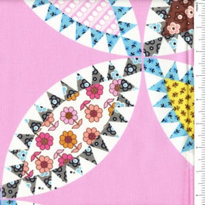 May include: A pink fabric featuring a repeating pattern of large, curved petal shapes filled with floral prints in shades of pink, orange, yellow, and brown, bordered by blue and grey triangles. A ruler shows a scale of approximately 8 inches.