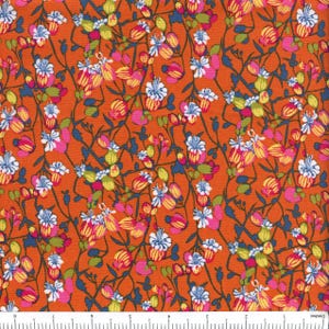 May include: Close-up of orange fabric with a floral pattern. The design features pink, white, yellow, and blue flowers with green leaves and dark blue stems. The fabric is likely cotton or a similar material.