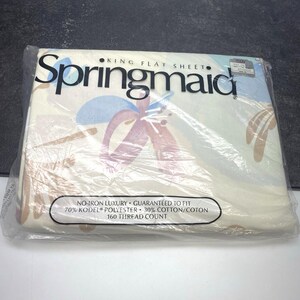 Könnte beinhalten: Ein verpacktes King-Flachbettlaken von Springmaid. Das Laken ist weiß mit einem Blumenmuster in Rosa-, Blau- und Beigetönen. Die Verpackung enthält den Text „No-Iron Luxury“ und „160 Fadenzahl“.