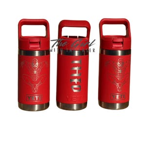 May include: A white ceramic mug with a black handle and the text "But First, Coffee" in a bold, black font. The mug is sitting on a wooden surface. The mug is approximately 4 inches tall.