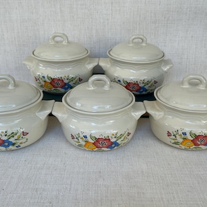 Puede incluir: Conjunto de cinco ollas de sopa de cerámica blanca con diseños florales en tonos rojos, amarillos, azules y verdes. Las ollas tienen tapas y son perfectas para servir sopa o estofado.