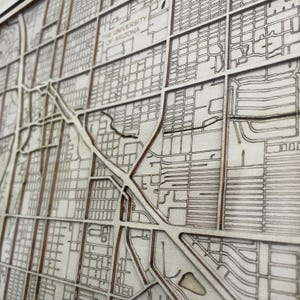 May include: A close-up of a laser-cut wooden map of The University of Arizona. The map shows the streets and buildings of the campus.