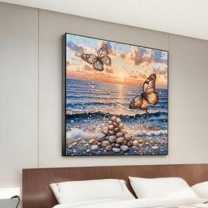 Puede incluir: Una pintura que representa un paisaje marítimo con dos mariposas volando sobre una pila de piedras lisas y blancas. El cielo es de un naranja y rosa vibrantes, con nubes. El océano es de un azul profundo, con olas rompiendo en la orilla.