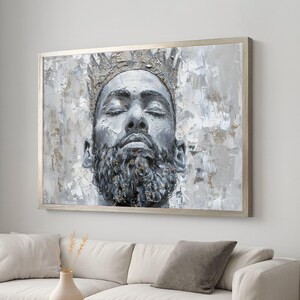 May include: A framed wall art print depicting a grayscale portrait of a man with closed eyes, a beard, and a crown. The artwork has a textured, impasto style with shades of grey, white, and gold. The frame is a light silver colour.