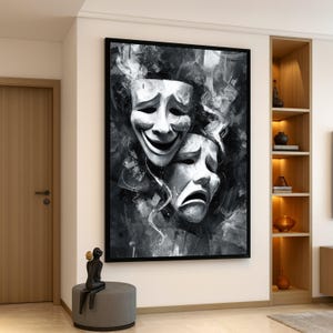 May include: Black and white framed artwork featuring two theatrical masks, one smiling and one frowning. The masks are set against an abstract, smoky background. The artwork is displayed on a white wall in a modern interior setting.
