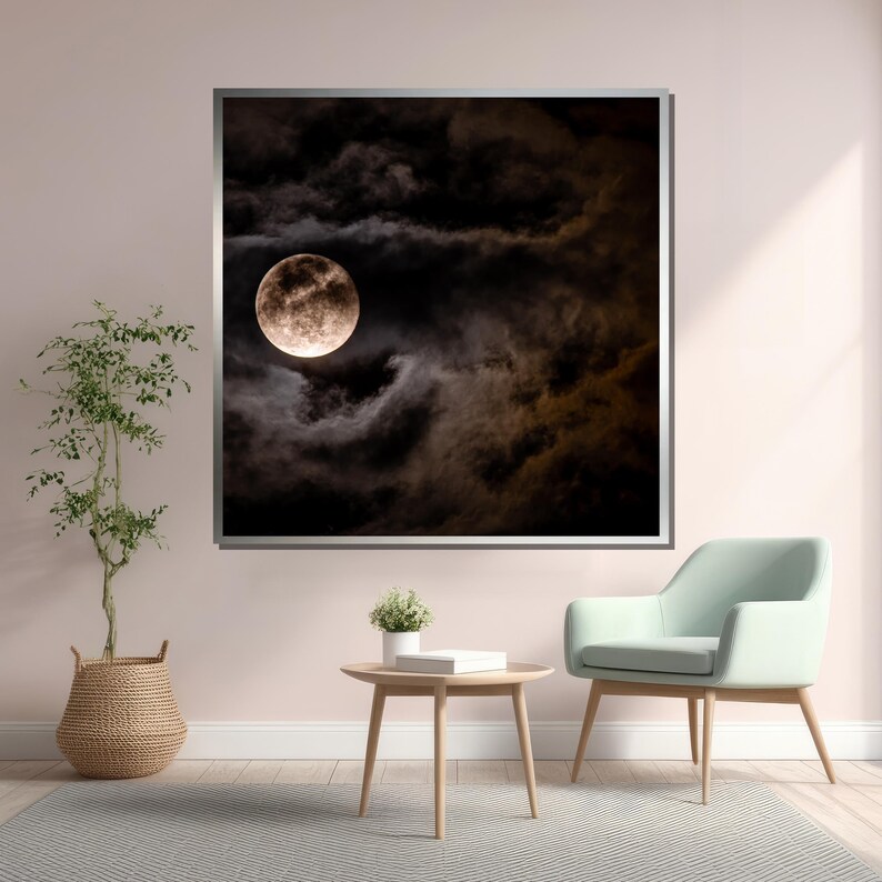 Puede incluir: Una fotograf&iacute;a enmarcada de una luna llena en un cielo oscuro y nublado. La luna es de color amarillo p&aacute;lido y est&aacute; parcialmente oscurecida por las nubes. La fotograf&iacute;a est&aacute; colgada en una pared rosa claro sobre una mesa de caf&eacute; marr&oacute;n claro y un sill&oacute;n verde claro.
