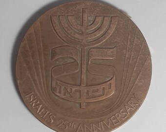 Puede incluir: Una medalla de bronce que conmemora el 25 aniversario de Israel. La medalla presenta una menorá, la palabra hebrea para Israel, y el texto "Israel's 25th Anniversary".