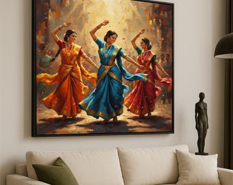 May include: A framed canvas print showing three women in vibrant traditional Indian dress dancing. They wear orange, blue, and red saris with gold detailing. The background features a crowd and confetti, suggesting a festive occasion.