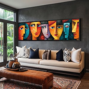 May include: A framed abstract art piece featuring a series of stylized faces in vibrant colors. The artwork, with a black frame, hangs above a beige sofa adorned with decorative pillows. The room has a modern aesthetic with dark gray walls and a leather ottoman.